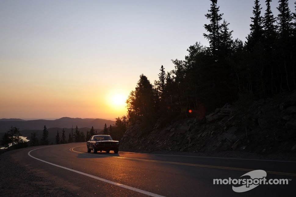 The sun rises over a vintage Ford Mustang